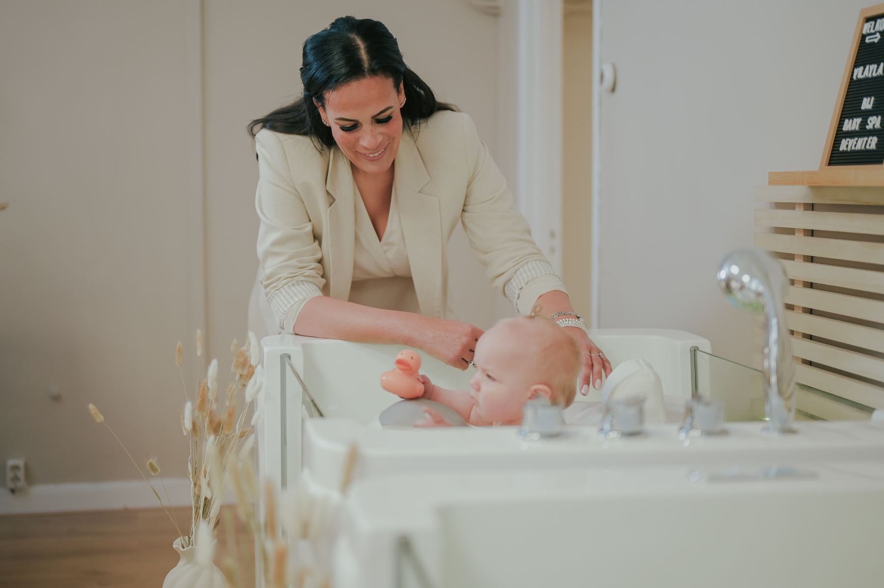 Maureen leunt liefdevol over baby in het bad