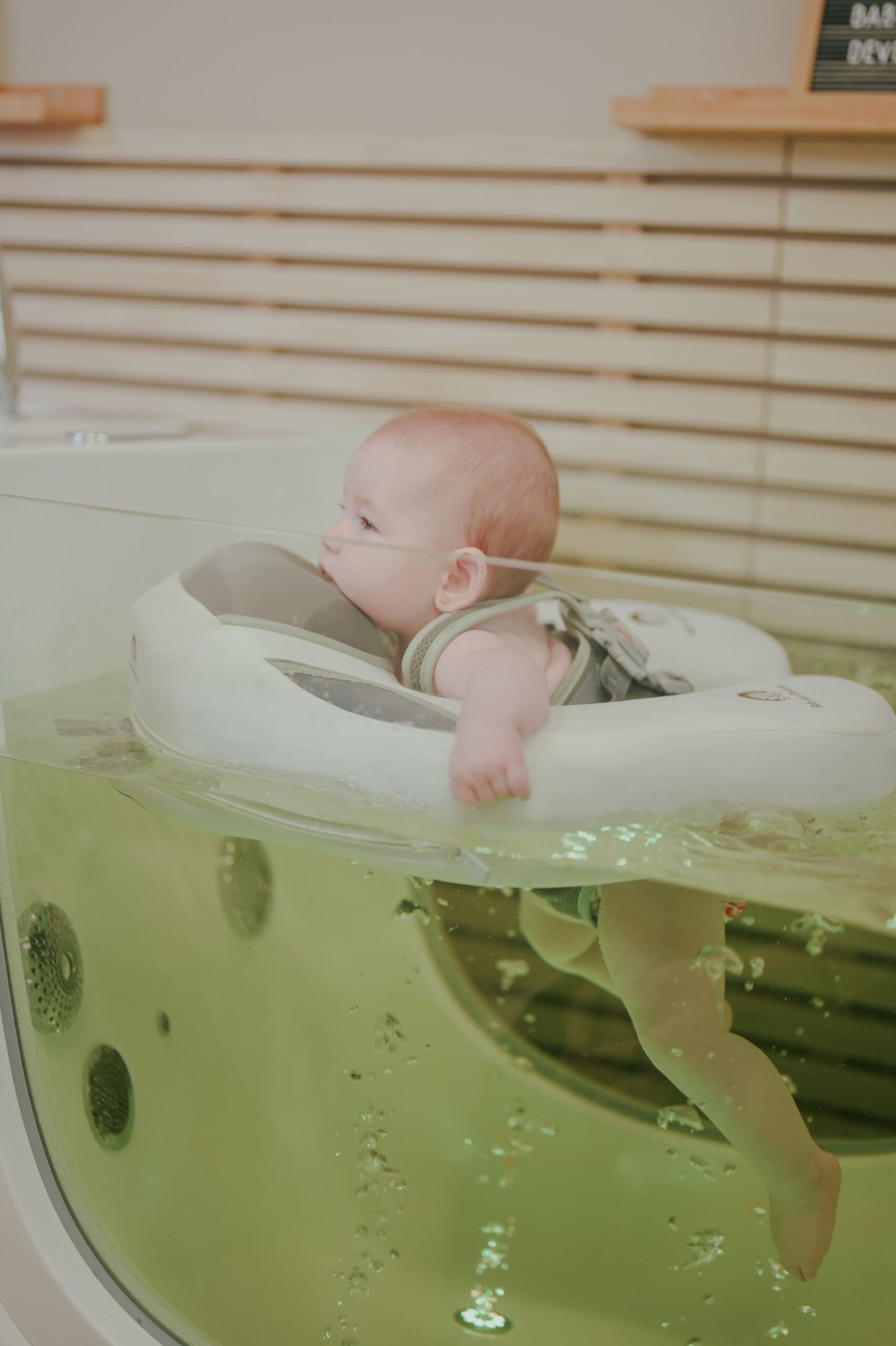 Baby in floatbad met welkomstbord bij Baby Spa Deventer