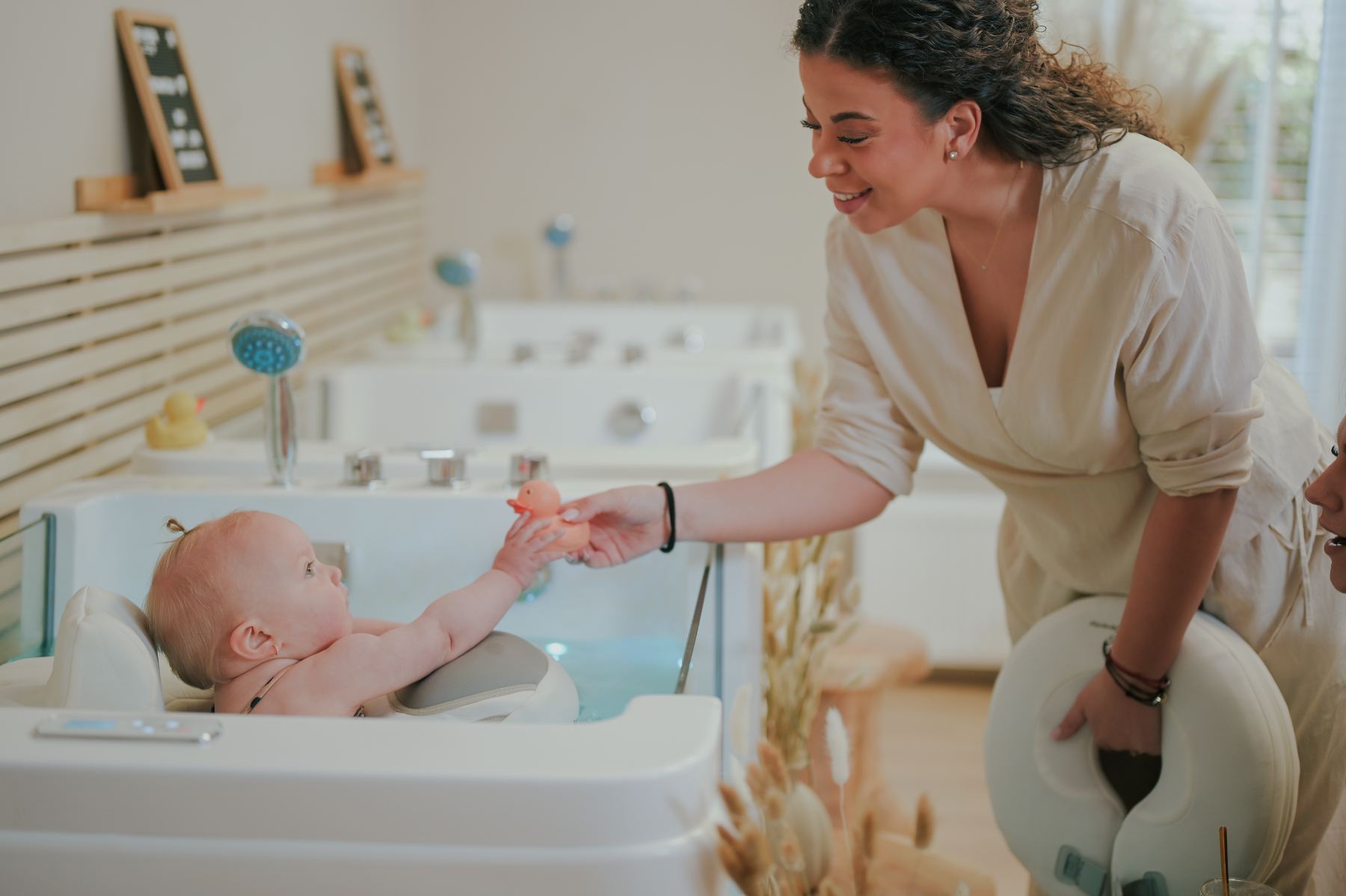 Shania reikt een rubber eendje aan een baby in het floatbad bij Mother Nature Spa Deventer