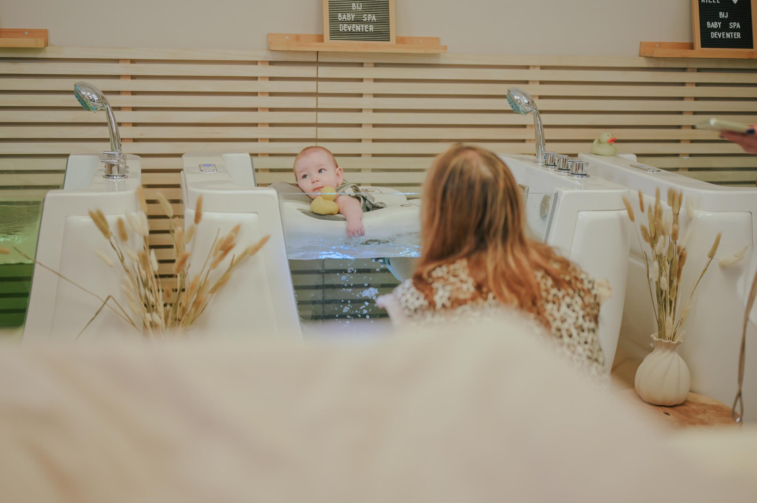 Baby in floatbad met welkomstbord bij Baby Spa Deventer